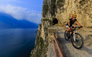 Radfahrer auf Bergpfad mit Seeblick.