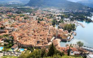 Panoramablick auf eine italienische Stadt am See, umgeben von Bergen.