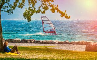 Entspannte Person im Schatten, Windsurfen auf dem See.