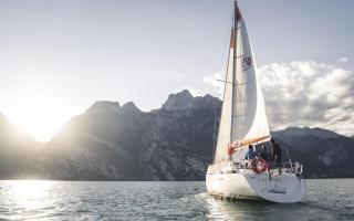 Segelboot gleitet bei Sonnenuntergang vor majestätischen Bergen.