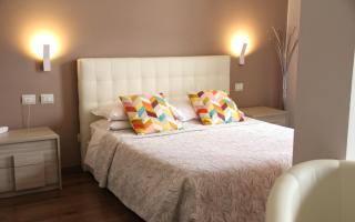 Camera da letto moderna con cuscini colorati e luci soffuse.