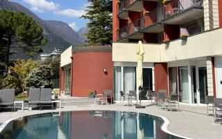 Hotel con piscina e vista montagna, cielo sereno.