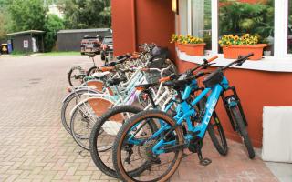 Biciclette colorate parcheggiate, atmosfera accogliente e fiori vivaci adornano il luogo.