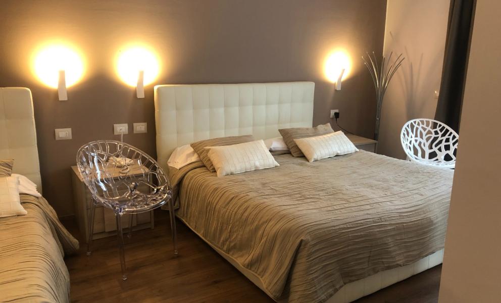 Modernes Zimmer mit Doppelbetten und transparenten Stühlen.