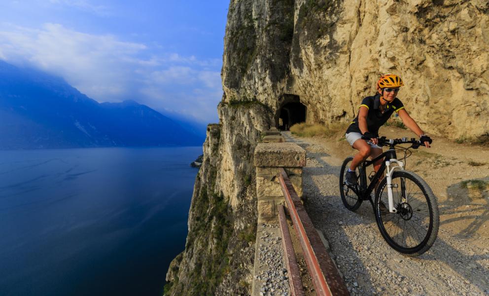 Radfahrer auf Bergpfad mit Seeblick.