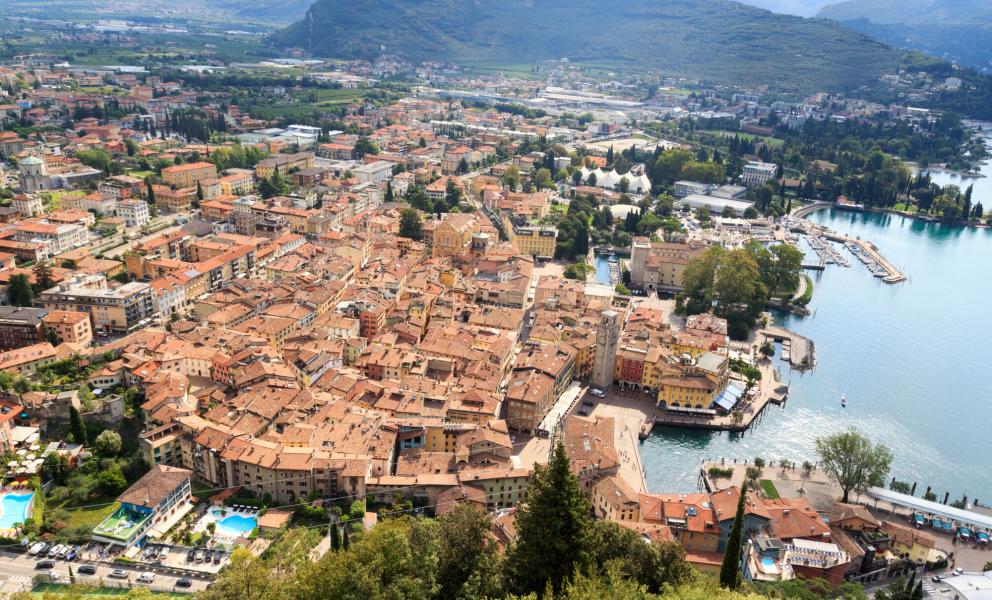 Panoramablick auf eine italienische Stadt am See, umgeben von Bergen.