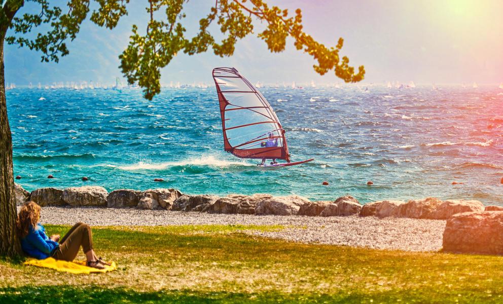 Entspannte Person im Schatten, Windsurfen auf dem See.