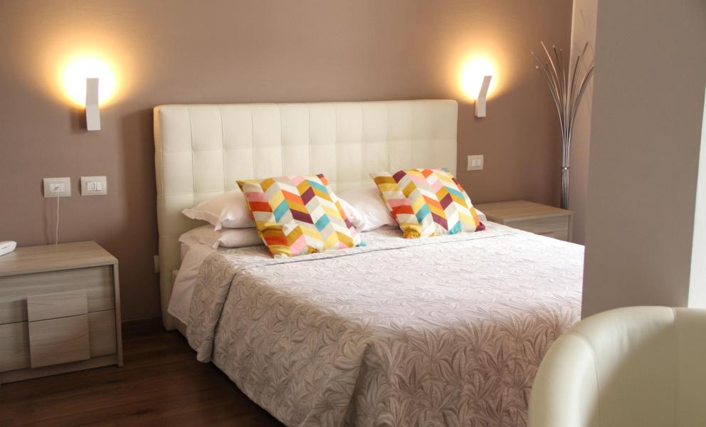 Camera da letto moderna con cuscini colorati e luci soffuse.