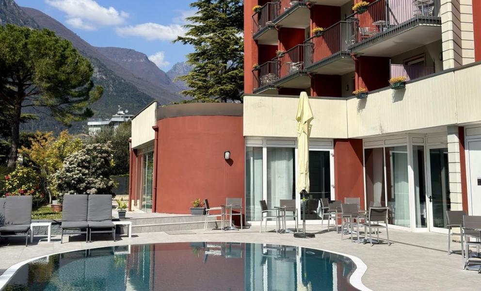 Hotel con piscina e vista montagna, cielo sereno.