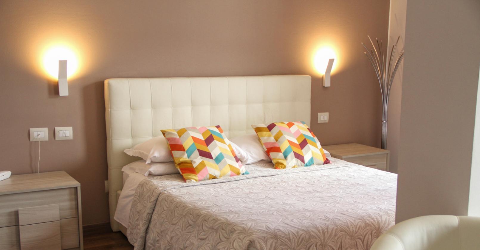 Camera moderna con letto matrimoniale e cuscini colorati.