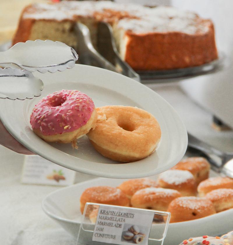 Two donuts on a plate, one pink and one plain.