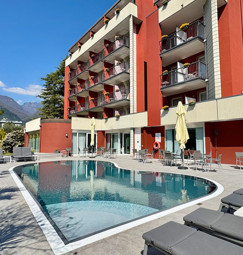 Hotel elegante con piscina e vista montagna, atmosfera rilassante e soleggiata.