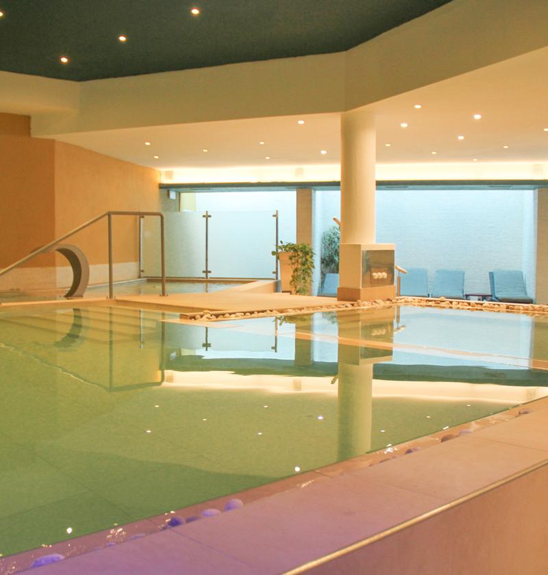 Moderna piscina interna con illuminazione soffusa e design elegante.